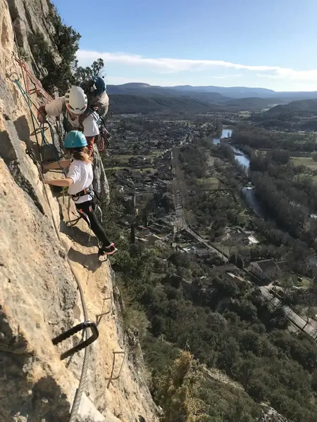Petite fille encadrée par un moniteur sur via ferrata avec vue sur saint bauzille de putois