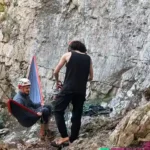 Grimpeur en pied de falaise dans un hamac